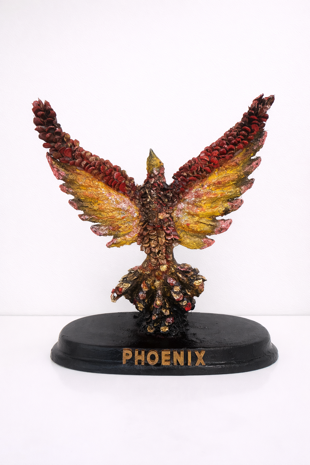 Phoenix figurine made with pinecones with colorful wings on a white background